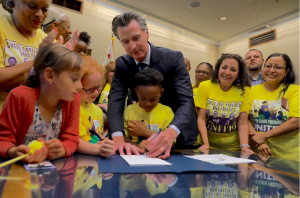Surrounded by children, Governor Newsom signs child care worker legislation.