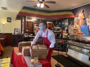 Governor Newsom places a stack of boxed meals onto a red table. 