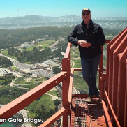 Governor Gavin Newsom stands at the top of the Golden Gate Bridge with a view of San Francisco behind him. He's wearing a ball cap, sunglasses, and jeans as he smiles. Text on the images states Golden Gate Bridge.