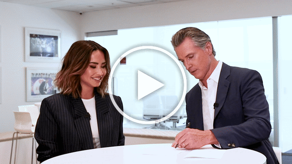 Demi Lovato and Governor Newsom hold up signed legislation