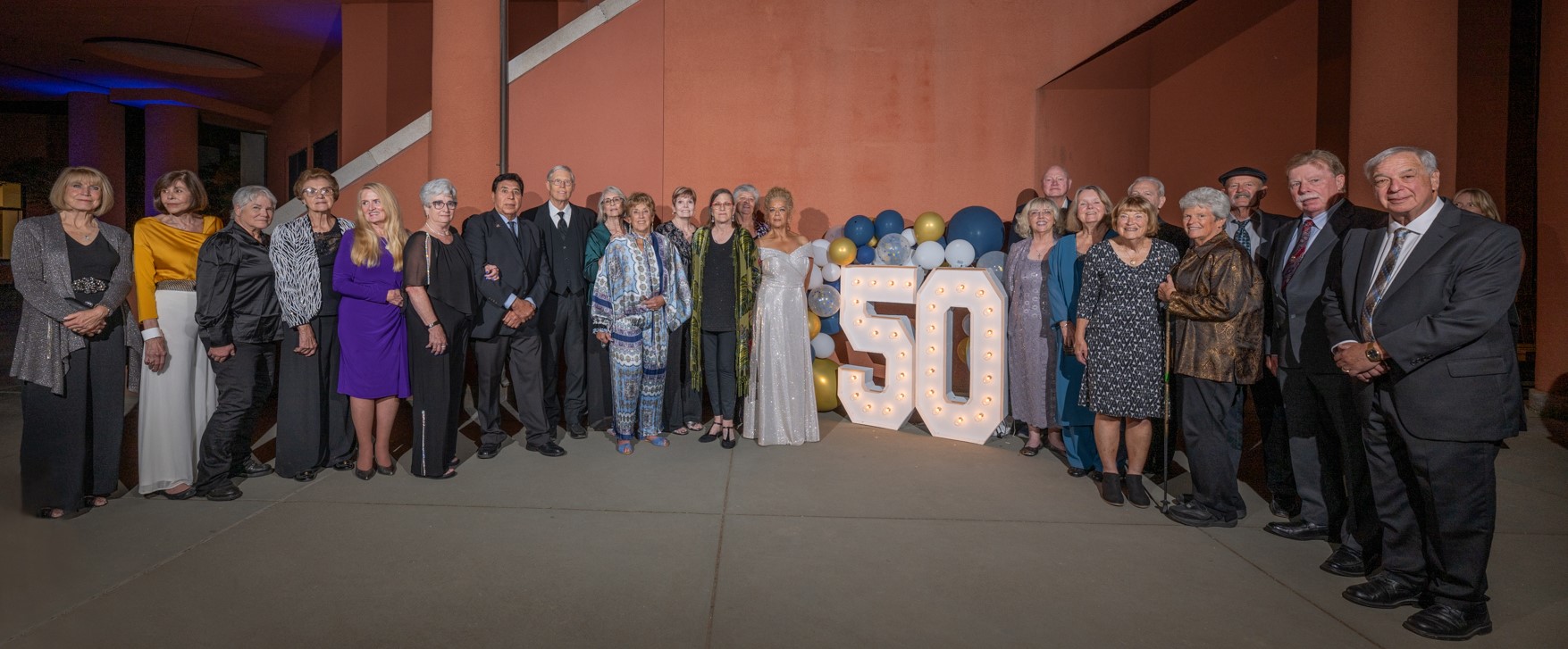 Group of people standing near 50 sign and balloons