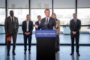 A photo with Governor Newsom and several individuals behind a podium with a sign that says efficient effective engaged.
