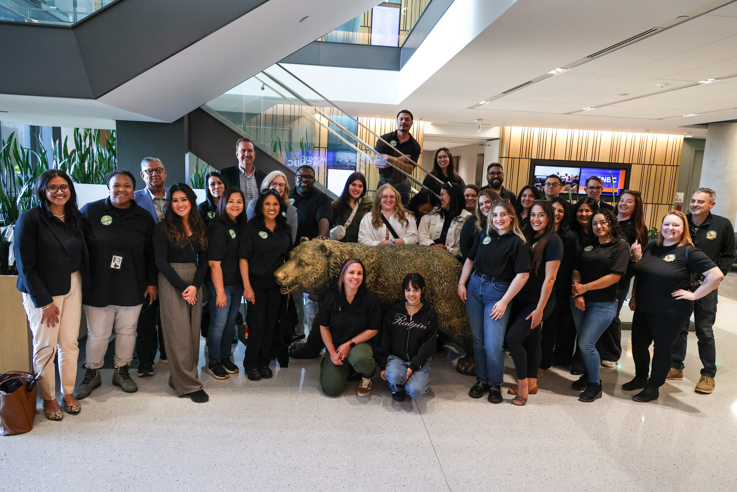 A photo of multiple individuals standing around a bear statue