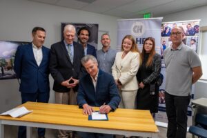 Image of Governor Gavin Newsom sitting a table signing a bill surrounded by 7 people standing up behind him