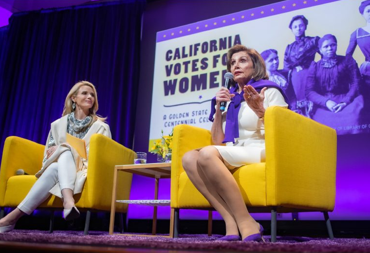 First Partner Jennifer Siebel Newsom and Congresswoman Nancy Pelosi sit on a panel in front of a sign that says “California Votes for Women”.